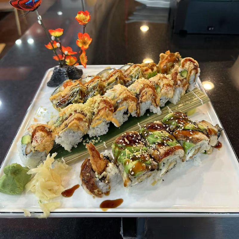 Hokkaido-Ramen-&-Sushi-Japanese-Restaurant-Assorted-Sushi-Rolls-Platter-Lubbock Platter of assorted sushi rolls garnished with flowers and sauces.