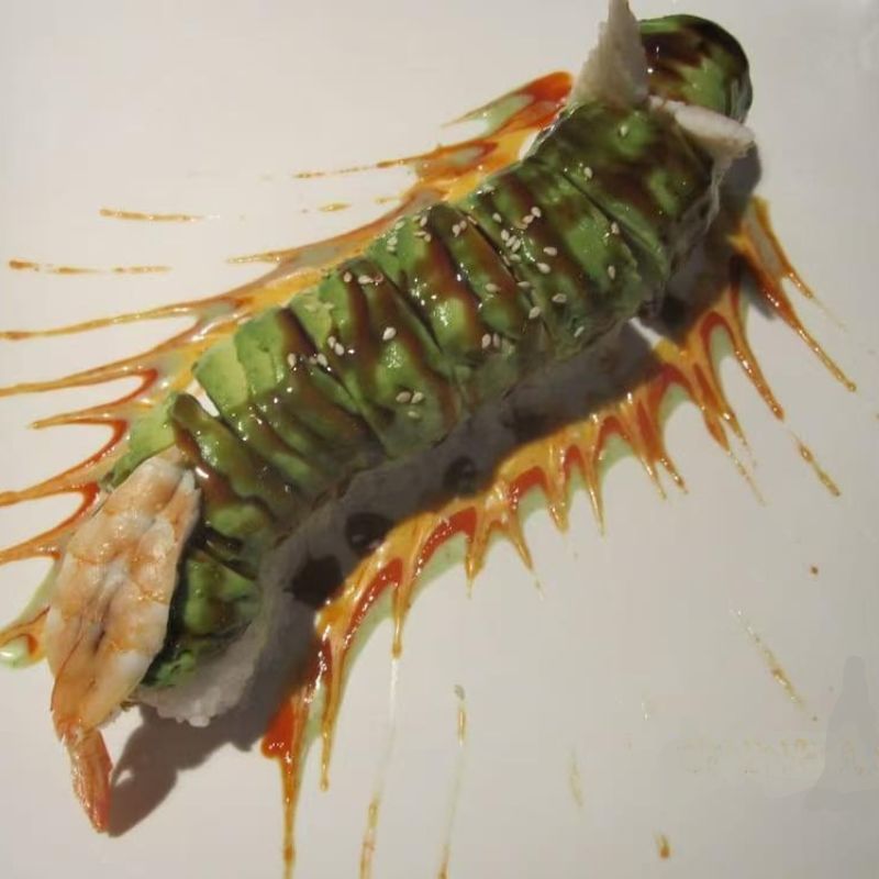 Avocado and shrimp sushi drizzled with sauces, unique in shape.