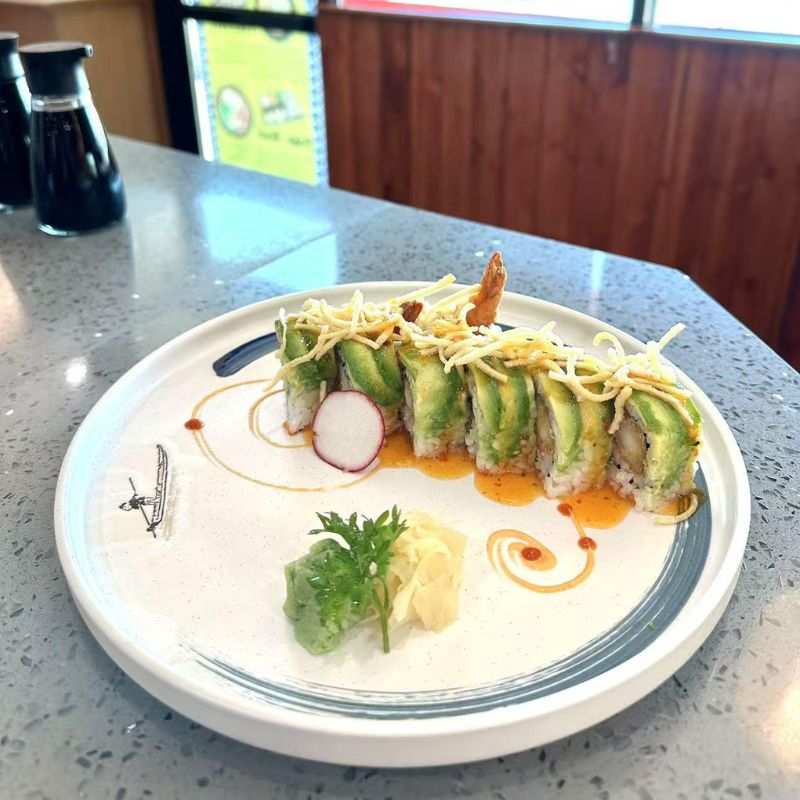 Hokkaido-Ramen-&-Sushi-Japanese-Restaurant-Avocado-Shrimp-Sushi-Roll-Lubbock Sushi roll topped with avocado, shrimp, and fried noodles, decorated neatly.