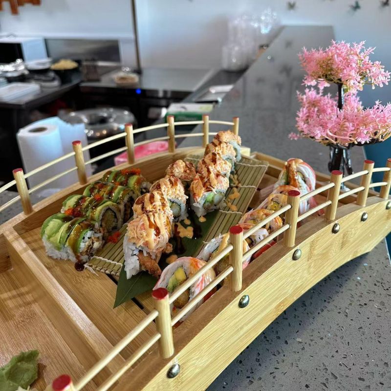 Hokkaido-Ramen-&-Sushi-Japanese-Restaurant-Bridge-Shaped-Sushi-Platter-Lubbock Sushi rolls placed on a bridge - shaped wooden tray, nicely decorated.