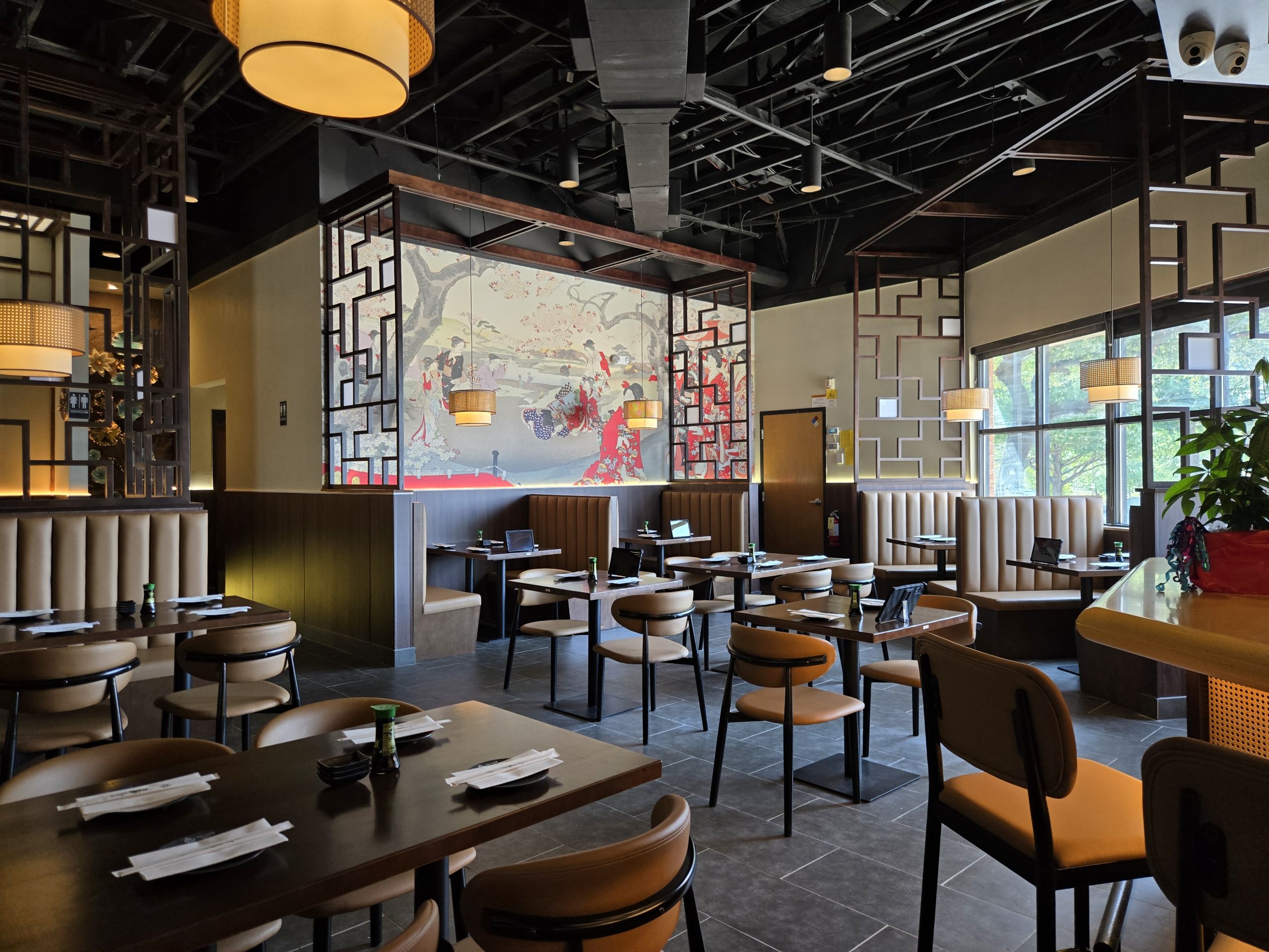 Modern interior of Hokkaido Sushi restaurant featuring dining tables, booths, and a traditional Japanese mural.