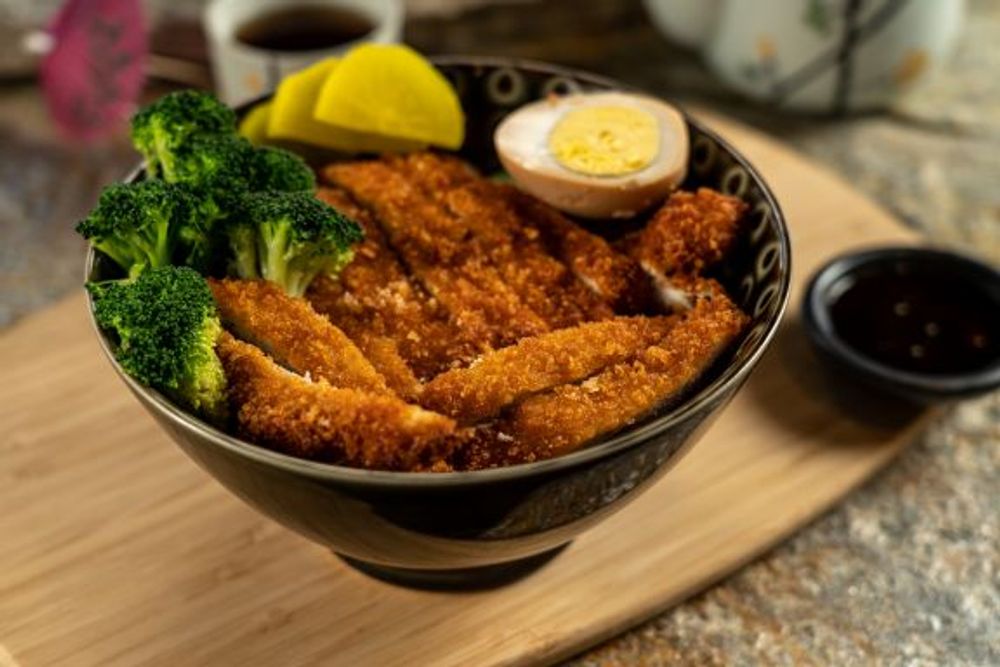Crispy tonkatsu pork cutlet rice bowl with broccoli, pickles and soft boiled egg at Hokkaido Sushi Bar, a Japanese Restaurant in Vancouver