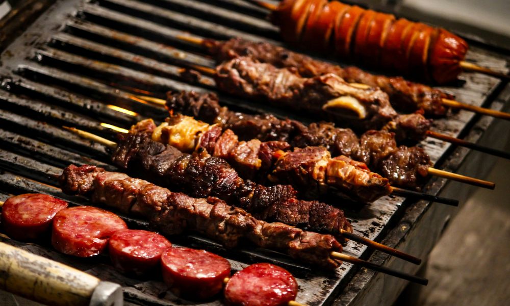 Grilled skewers of meat and sausage cooking on a grill at Hot Point The Dalles, a Chinese restaurant in The Dalles