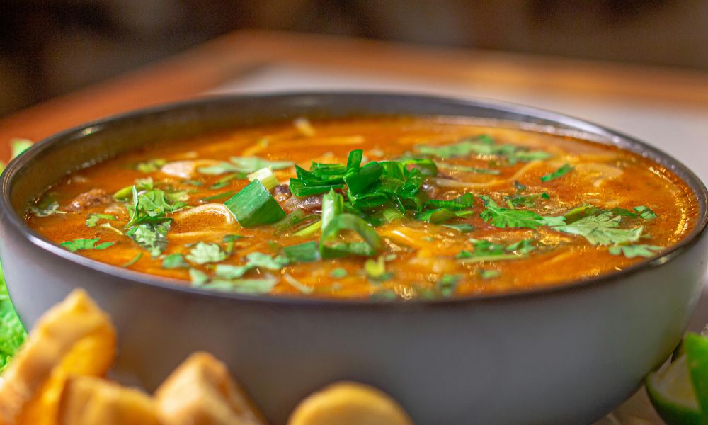 Spicy red soup garnished with green onions and cilantro at Hot Point The Dalles, a Chinese restaurant in The Dalles