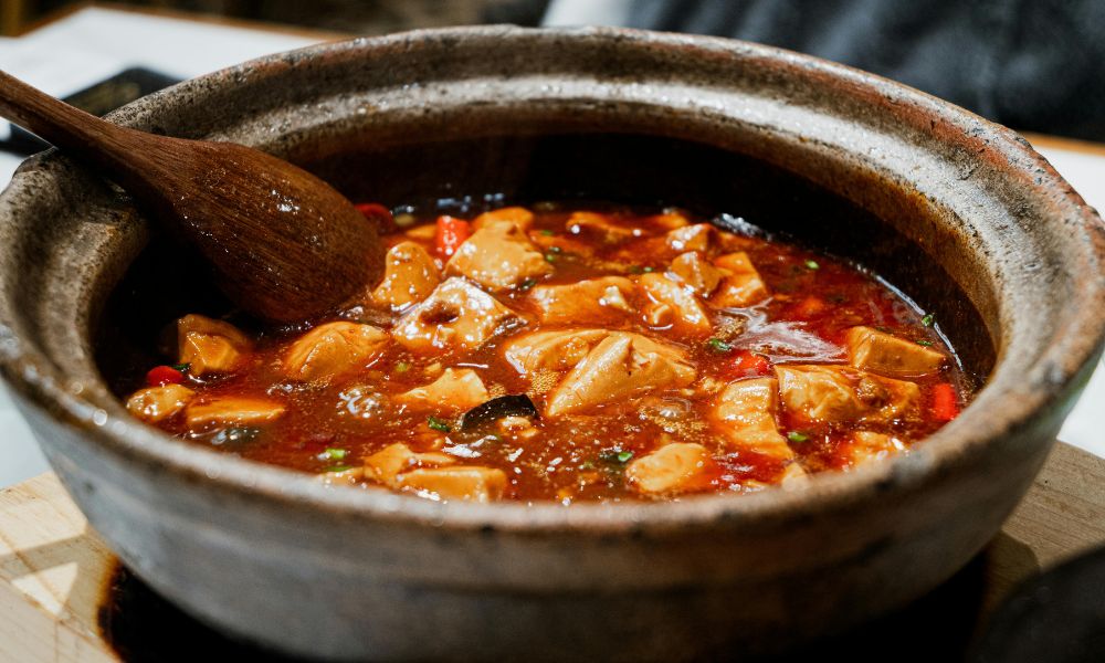 Spicy mapo tofu simmering in a stone pot with red sauce at Hot Point The Dalles, a Chinese restaurant in The Dalles
