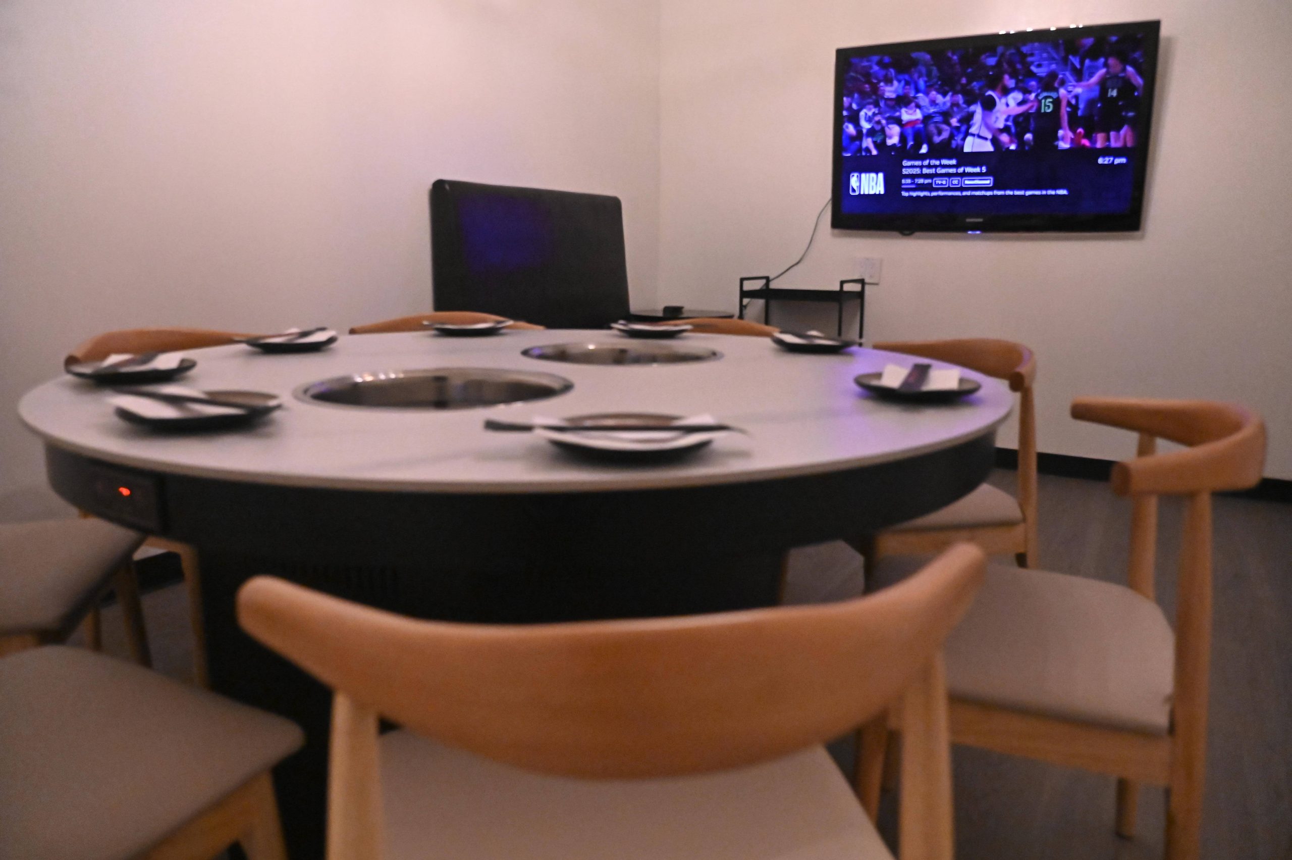 Indoor private dining area at Hotpot Bay (San Francisco Chinese hot pot restaurant): round table with personal hot pot stations and tableware, set up for premium beef & veggie hot pot set.