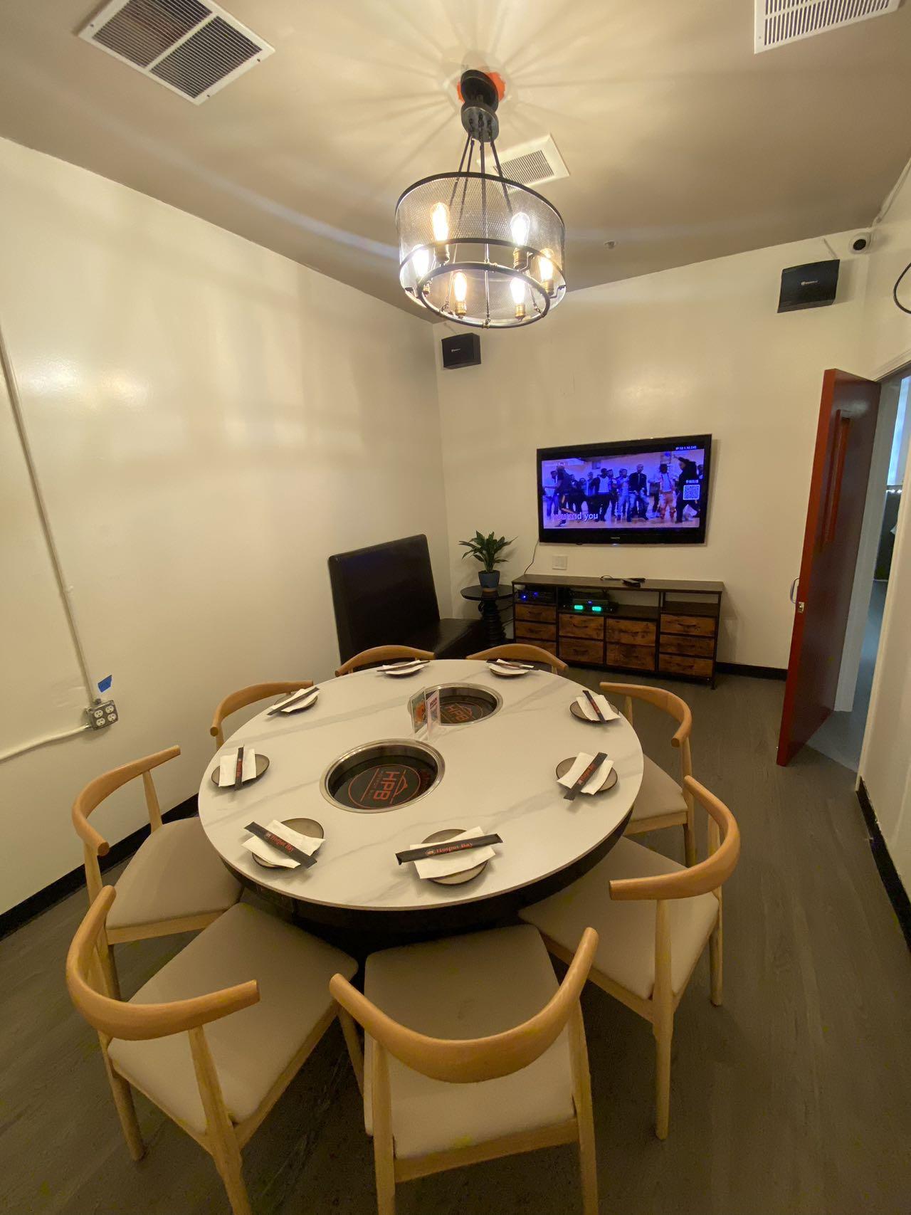 Indoor private dining area at Hotpot Bay (San Francisco Chinese hot pot restaurant): round table with personal hot pot stations and tableware, set up for premium beef & veggie hot pot set.