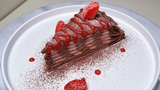 Chocolate crepe cake slice with strawberry sauce at TOZZARELLA, a Dessert restaurant in College Point