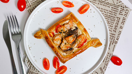 Shrimp and mushroom puff pastry tart on a white plate at TOZZARELLA, a Dessert restaurant in College Point