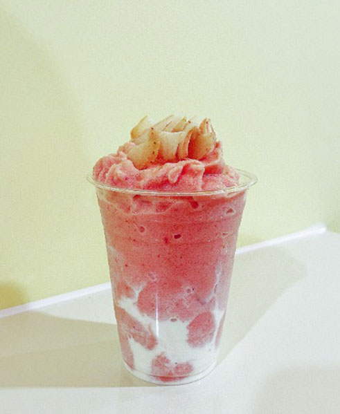 Pink frozen drink topped with lychee in a clear cup at TOZZARELLA, a Dessert restaurant in College Point