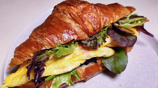 Classic egg croissant sandwich with leafy greens at TOZZARELLA, a Dessert restaurant in College Point