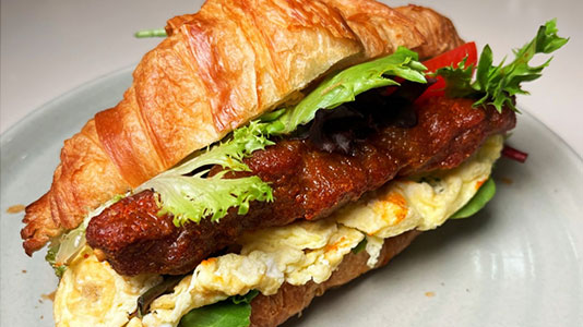 Savory croissant sandwich with meat patty and eggs at TOZZARELLA, a Dessert restaurant in College Point