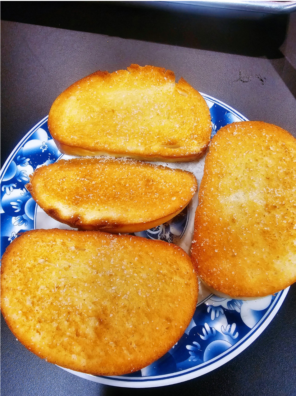 Fried bread slices topped with sugar on a blue patterned plate