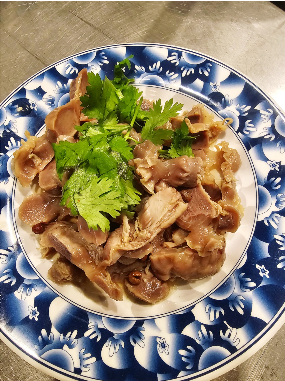 Sliced braised meat with cilantro on a blue and white patterned plate