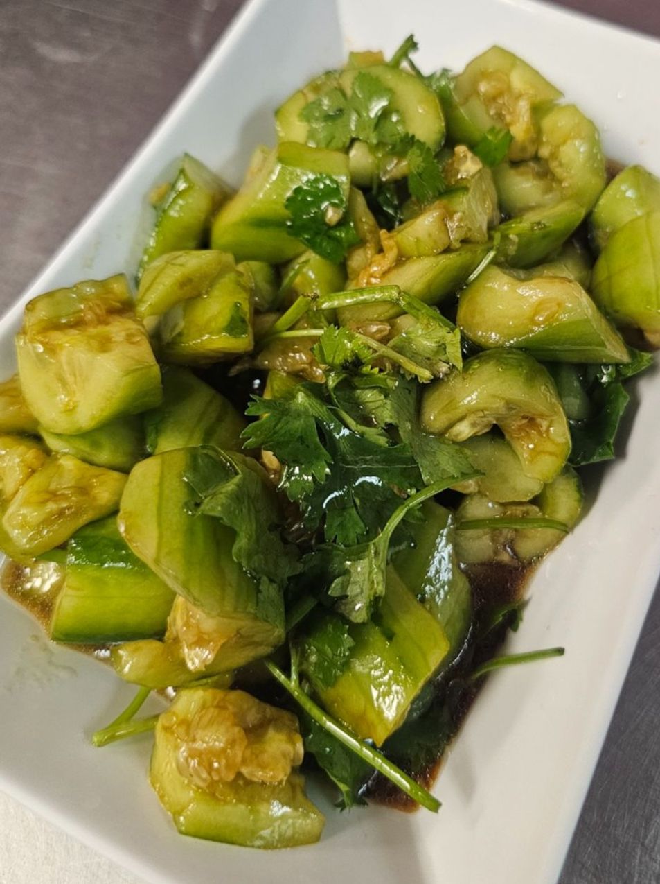 Smashed cucumber salad with cilantro and garlic in a white dish