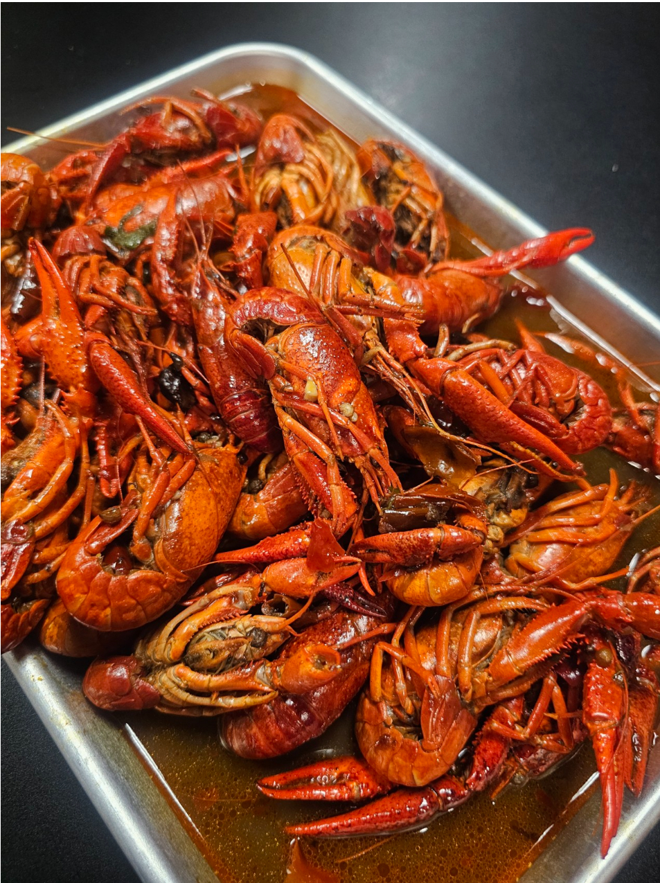 Spicy crawfish in a metal tray with sauce