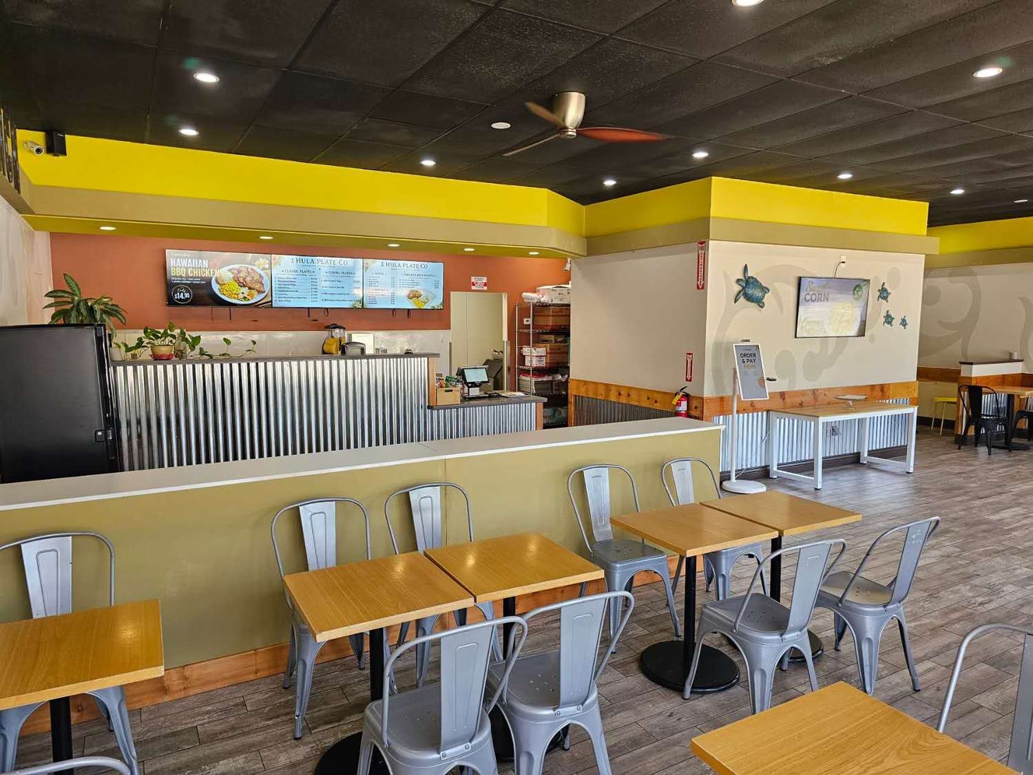 Dining seating area with tables and metal chairs inside at Hula Plate Co, a Hawaiian Restaurant in San Jose