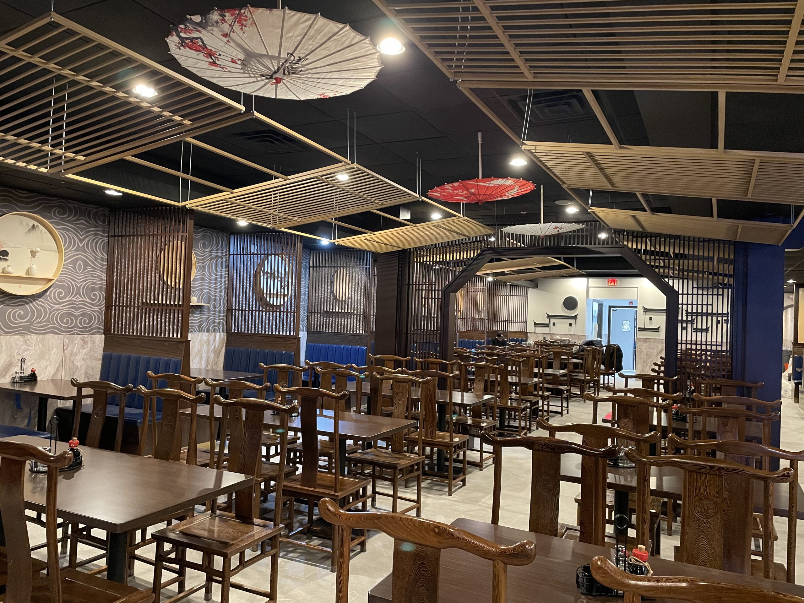 Spacious dining hall with wooden tables, chairs and decorative paper umbrellas overhead