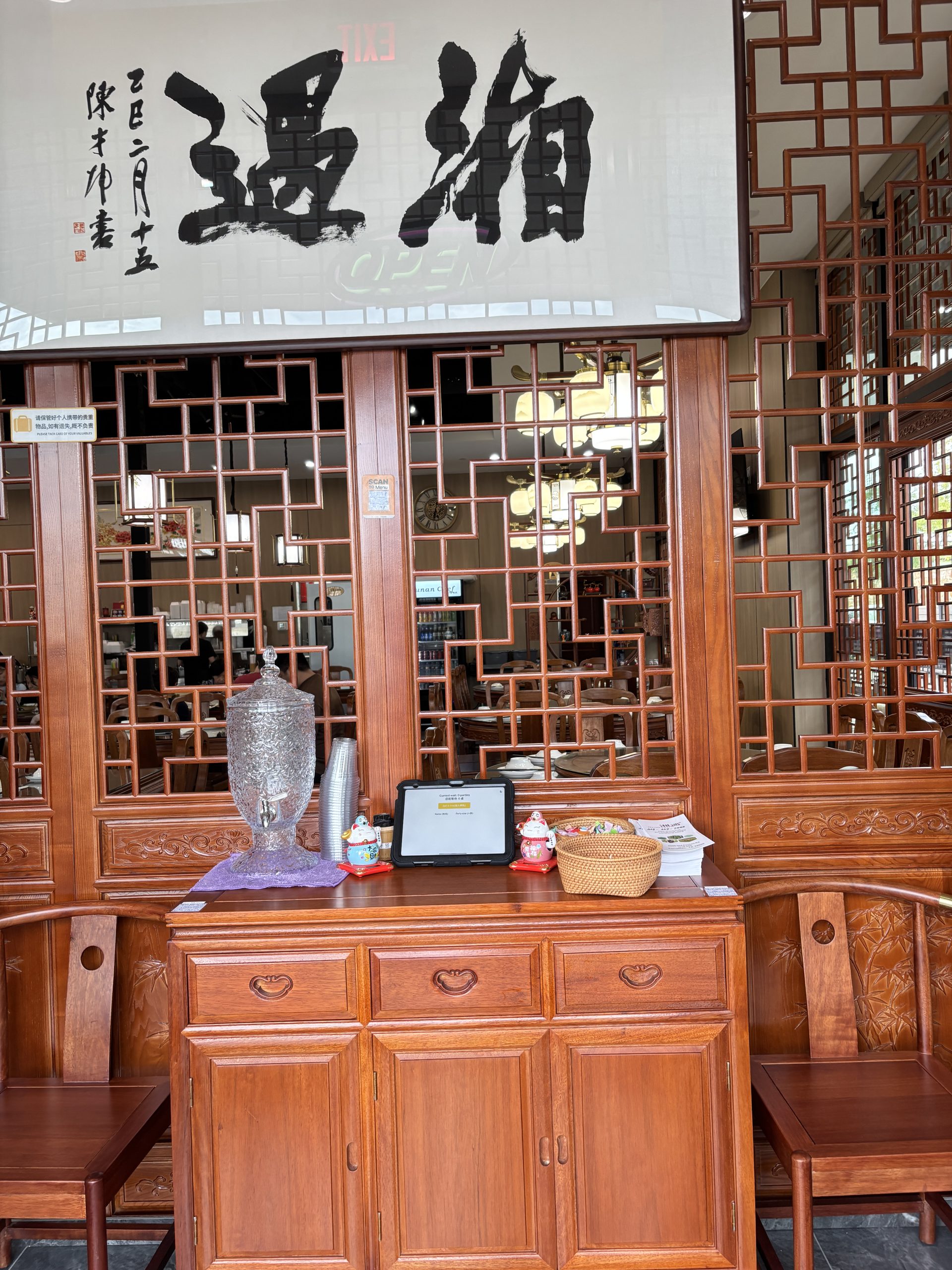 Interior entrance area with wooden furniture and calligraphy sign at Hunan Chef Xiang Yu, a Chinese Restaurant in Carrollton