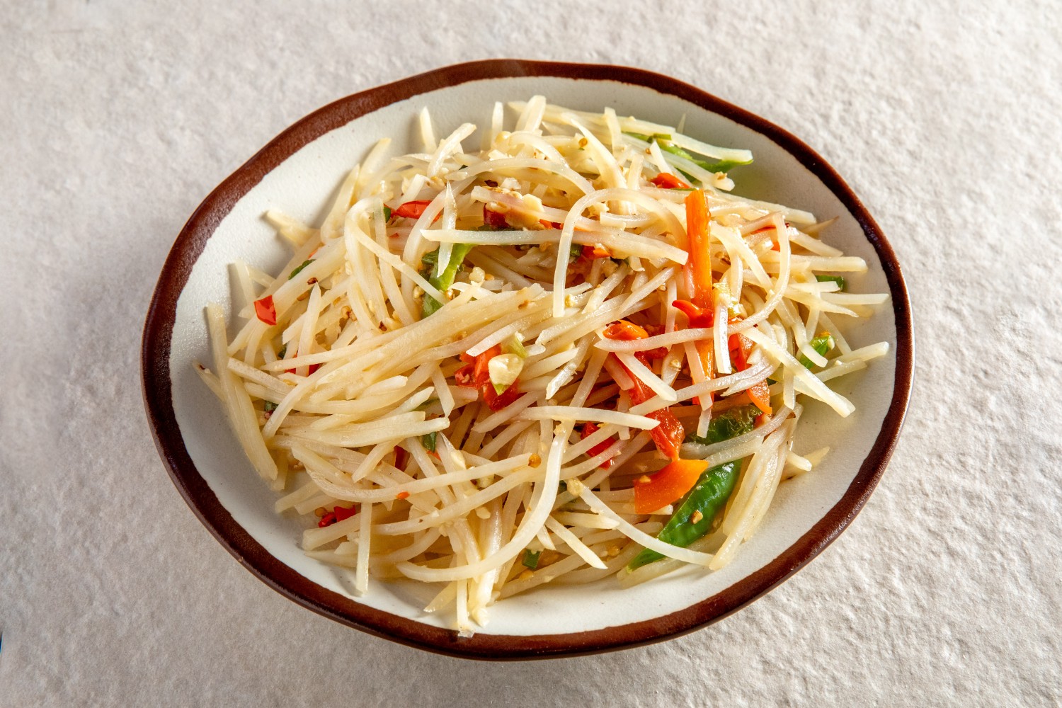 A bowl of shredded potato stir-fry with red and green chilies and garlic at Hunan Heat, a Chinese Restaurant in Long Island City