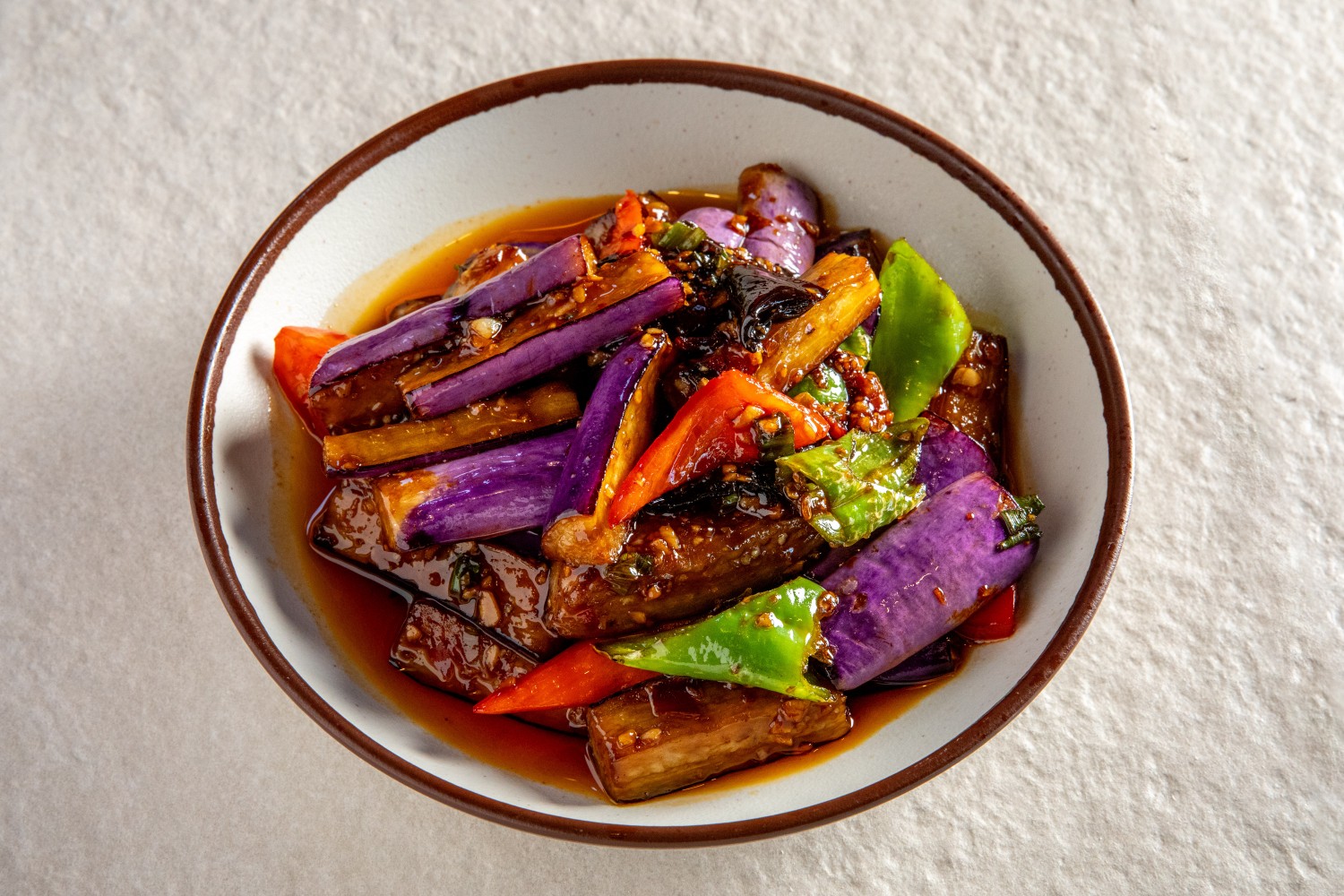 A bowl of fish-fragrant eggplant with purple skin, red and green peppers in glossy sauce at Hunan Heat, a Chinese Restaurant in Long Island City
