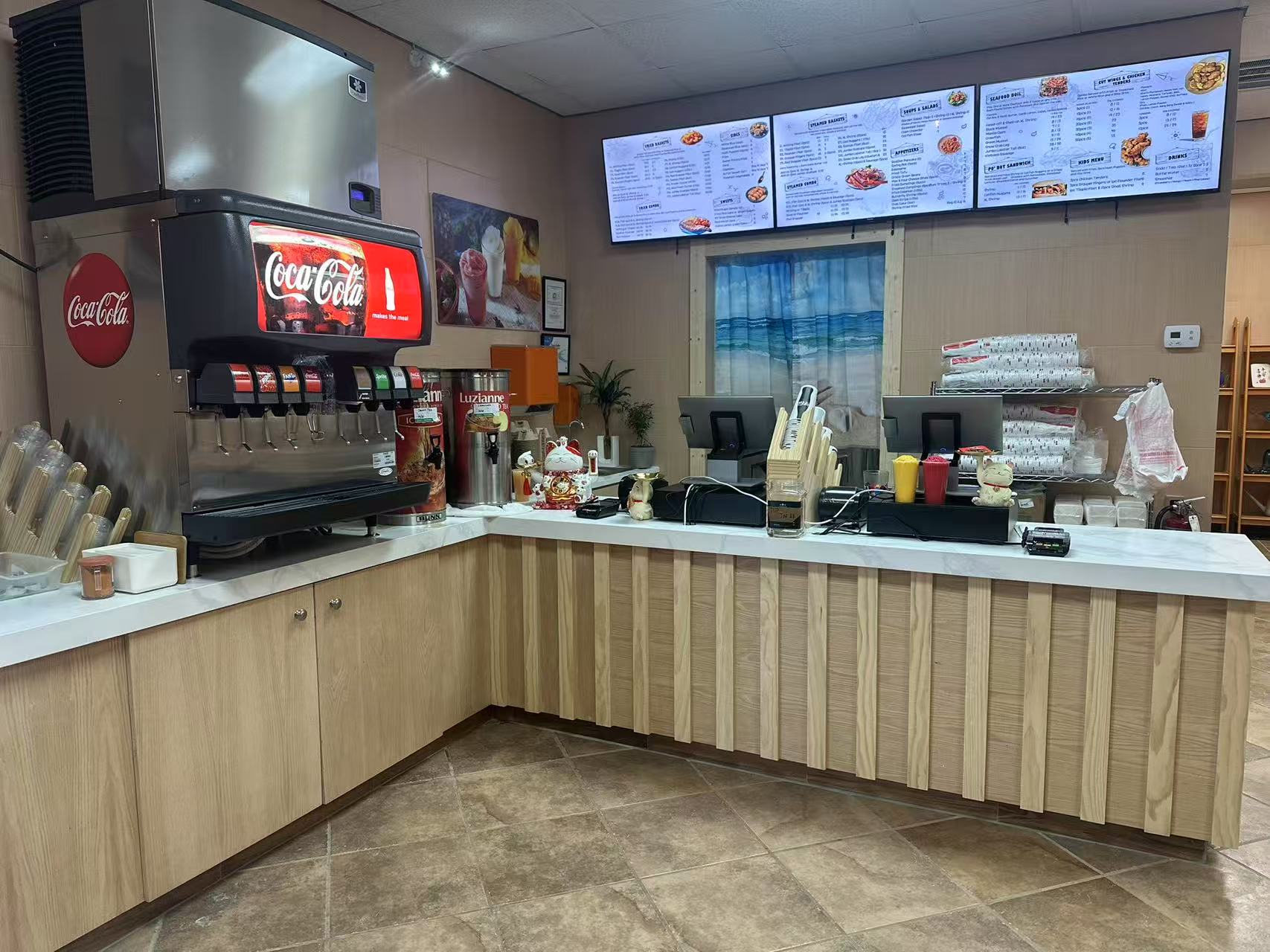 Restaurant counter with Coca-Cola machine and digital menu boards.