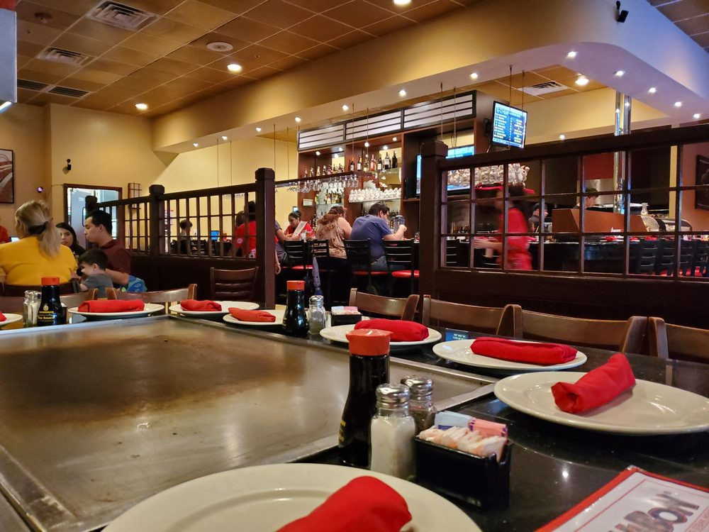 Indoor hibachi dining area with griddle tables, red napkins and seated guests at Ichibon Seafood & Steakhouse, a Japanese Restaurant in Pasadena