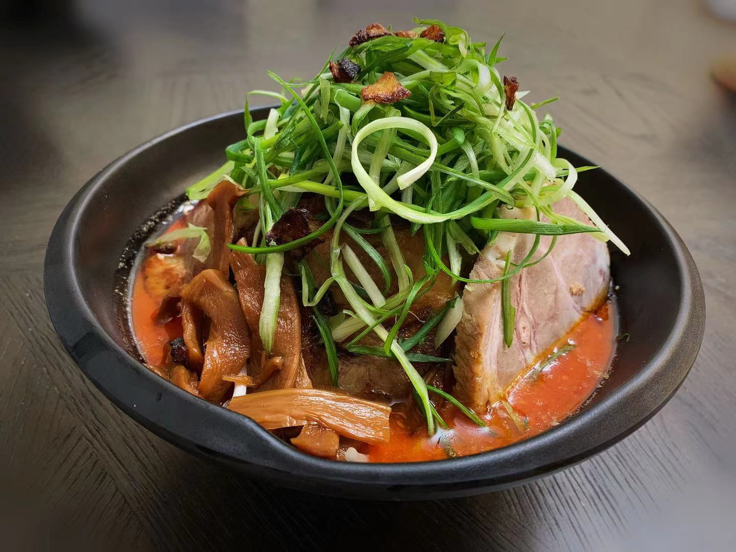 Spicy red‑broth ramen with pork, mushrooms and generous shredded green onion garnish at Ichitaru Ramen, a Ramen restaurant in Carlsbad