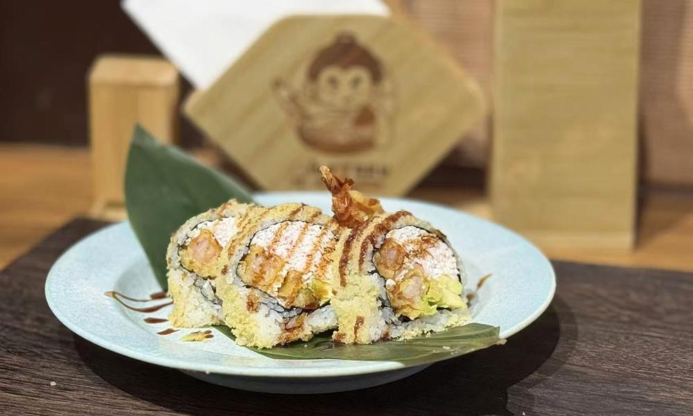 Crunchy tempura sushi roll with drizzled sauce presented on light blue ceramic plate at Ichitaru Ramen, a Ramen restaurant in Carlsbad