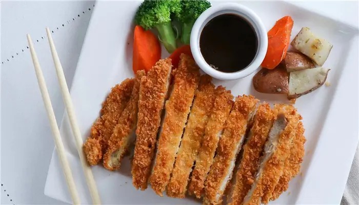 Crispy fried pork cutlet served with vegetables and sauce at Ikoi Sushi，a Sushi Restaurant in San Rafael