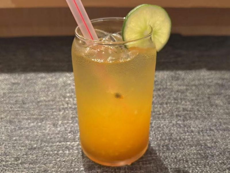Passion fruit lime green tea with a lime slice at Ikyu Sushi II, a Japanese Restaurant in New York.