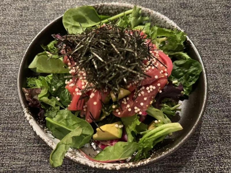 Bowl of salad with tuna, avocado, seaweed, and sesame seeds at Ikyu Sushi II, a Japanese Restaurant in New York.
