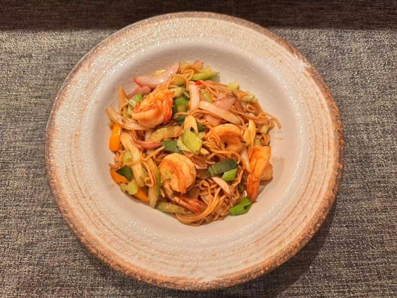 Bowl of yaki soba with shrimp and veggies at Ikyu Sushi II, a Japanese Restaurant in New York.