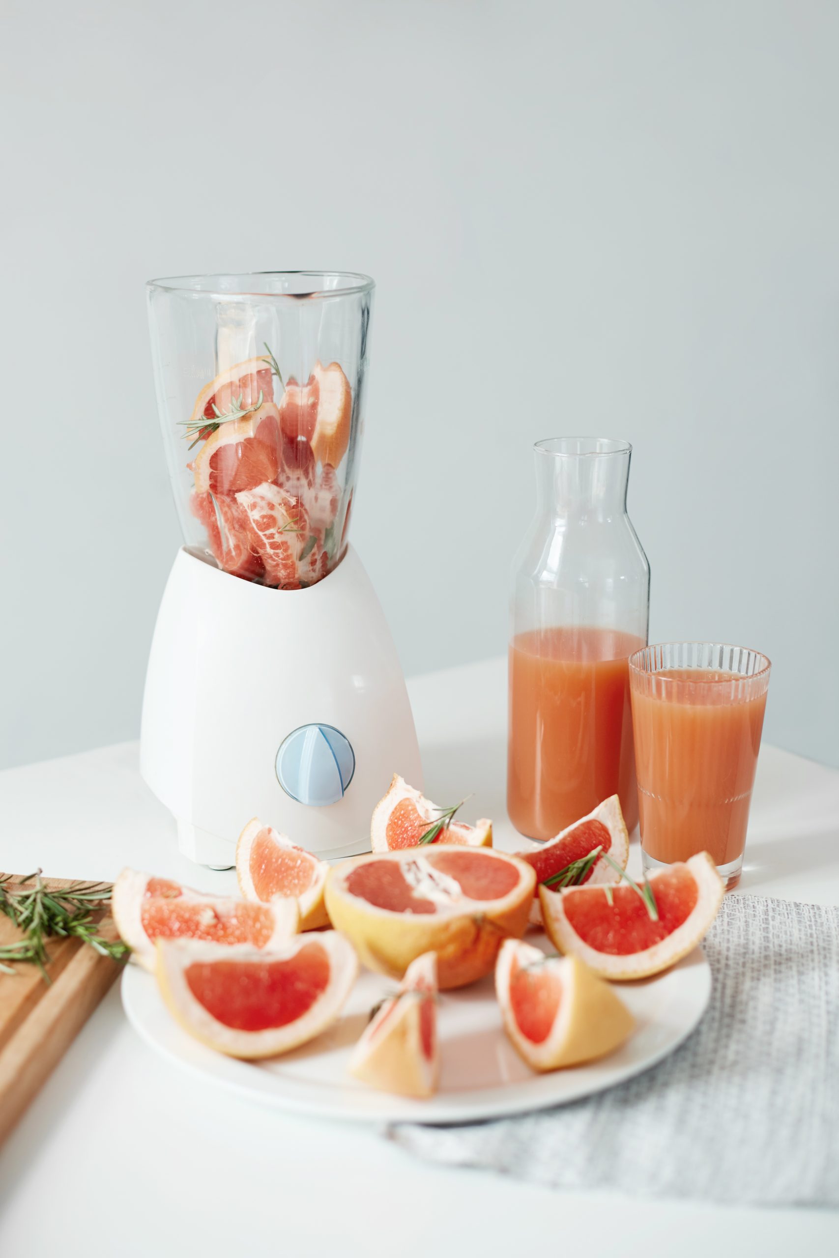 Inright-Tea-Inc-Pearl-milk-tea-shop-Great-Neck Blender with grapefruit and rosemary, fresh juice in glass, grapefruit pieces nearby.
