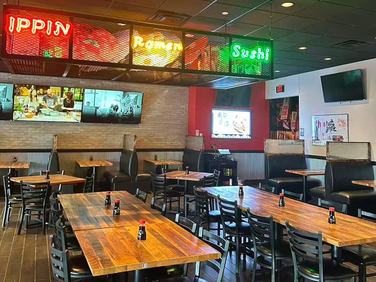 Spacious dining area with neon signs and TVs at Ippin Ramen & Sushi Bar, a Japanese Restaurant in Mankato
