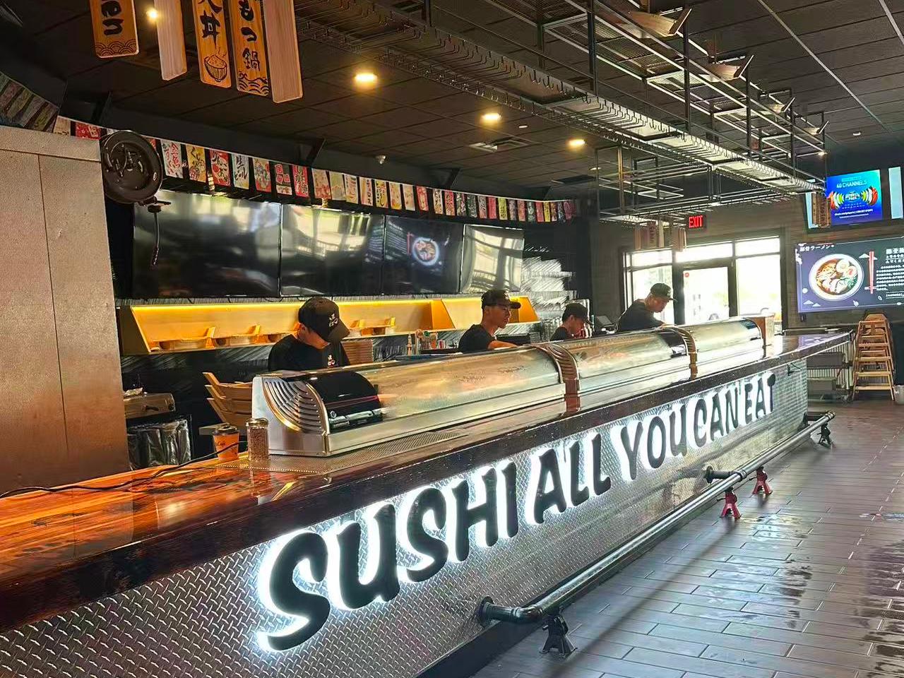 Sushi bar with "SUSHI ALL YOU CAN EAT" sign and chefs at work at Ippin Ramen & Sushi Bar, a Japanese Restaurant in Mankato
