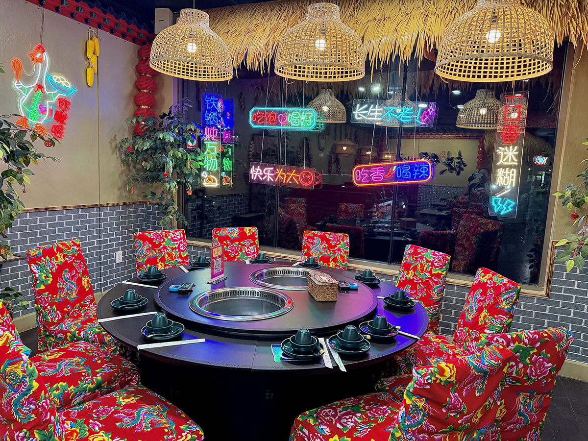 Neon-lit Chinese hot pot restaurant interior with floral seats at Iron Pot Stew Kitchen, a Chinese Restaurant in Santa Clara