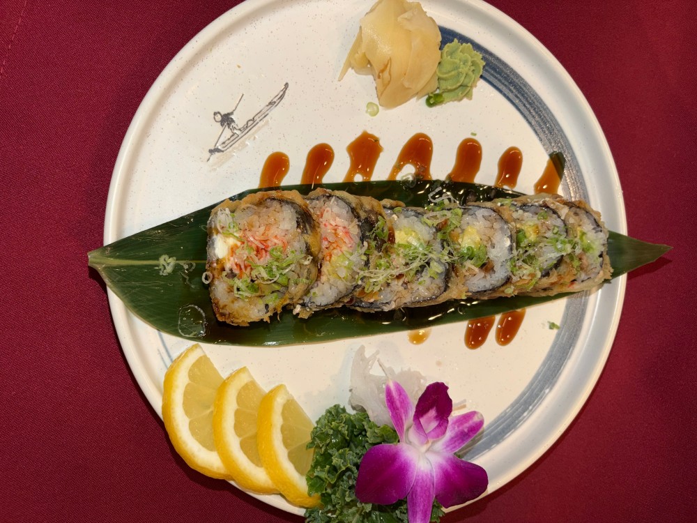 Deep fried sushi roll with eel sauce, orchid and lemon garnish