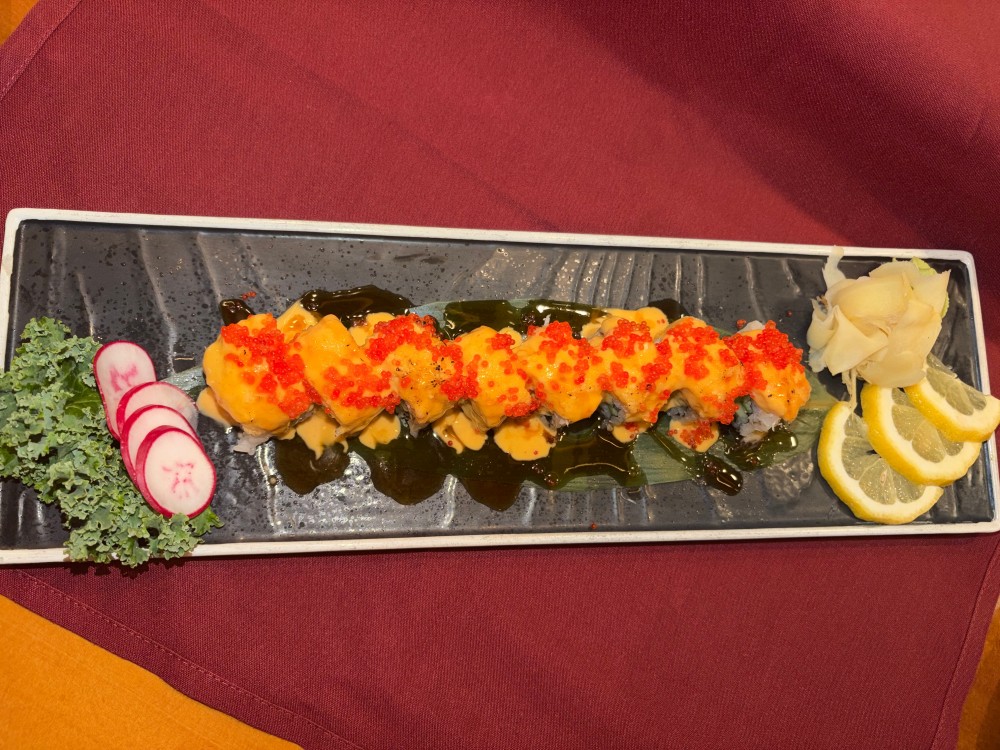 Sushi roll covered with creamy orange sauce and bright red tobiko