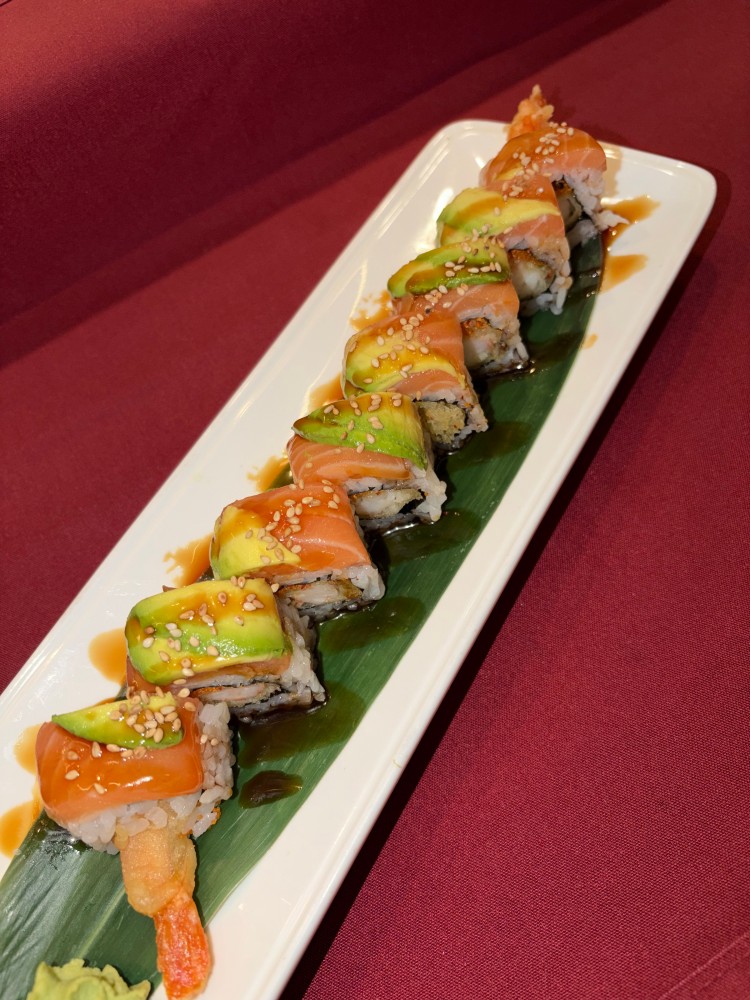 Sushi roll topped with salmon and avocado, with fried shrimp inside