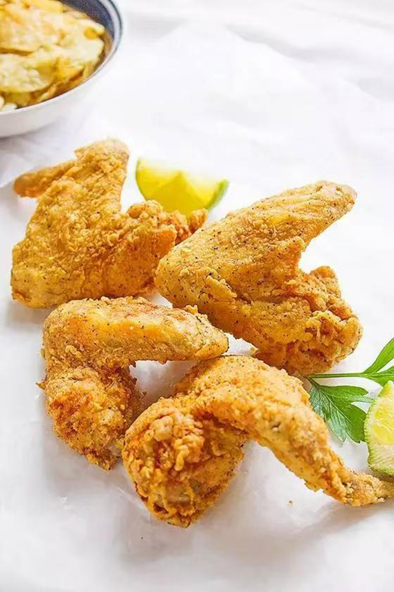Crispy seasoned deep-fried chicken wings with lime garnish at Jackie Chan's Chinese Restaurant in Philadelphia