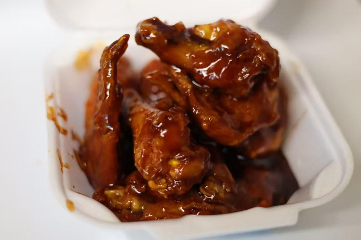 Glossy sauced chicken wings in takeout foam container at Jackie Chan's Chinese Restaurant in Philadelphia