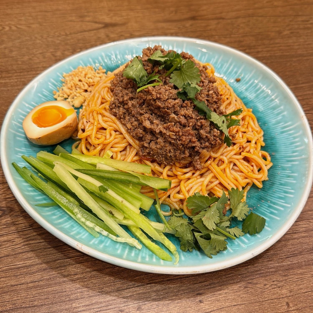 Dry noodles topped with meat mince, served with egg, cucumber strips, cilantro and crushed peanuts at JBC Rice Noodles Ramen & Dumplings, a Asian Restaurant in Astoria