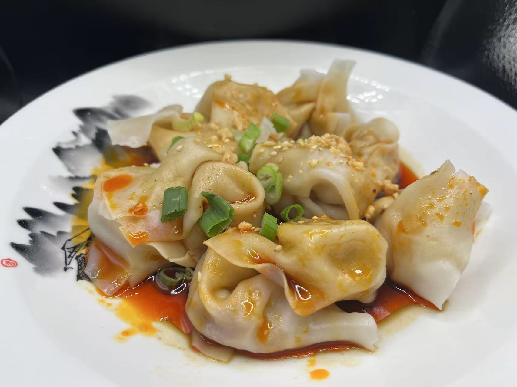 Spicy red oil wontons garnished with green onion and crushed peanut at JiangNan Philadelphia, a Chinese Restaurant in Philadelphi
