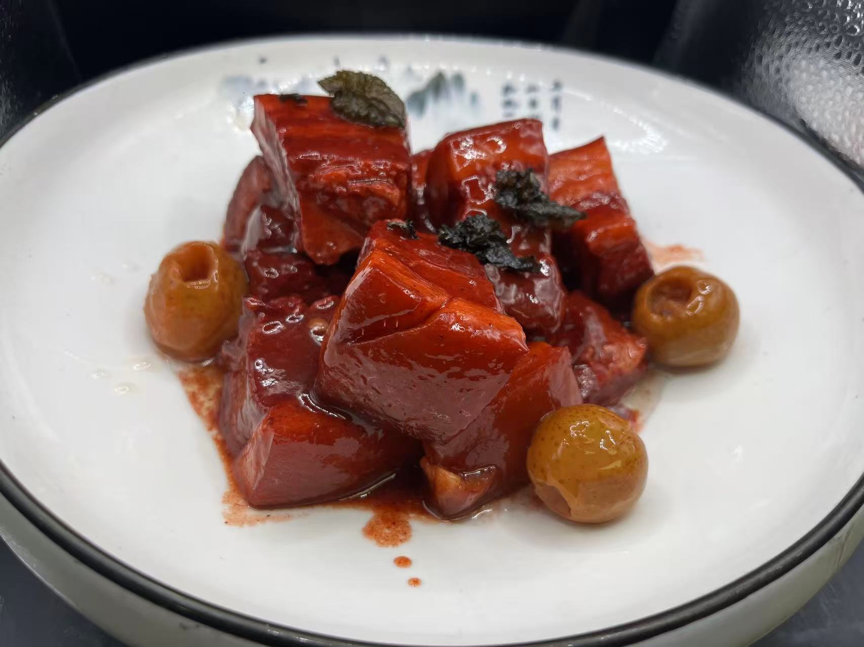 Braised red pork chunks with pickled fruit and herb garnish at JiangNan Philadelphia, a Chinese Restaurant in Philadelphi