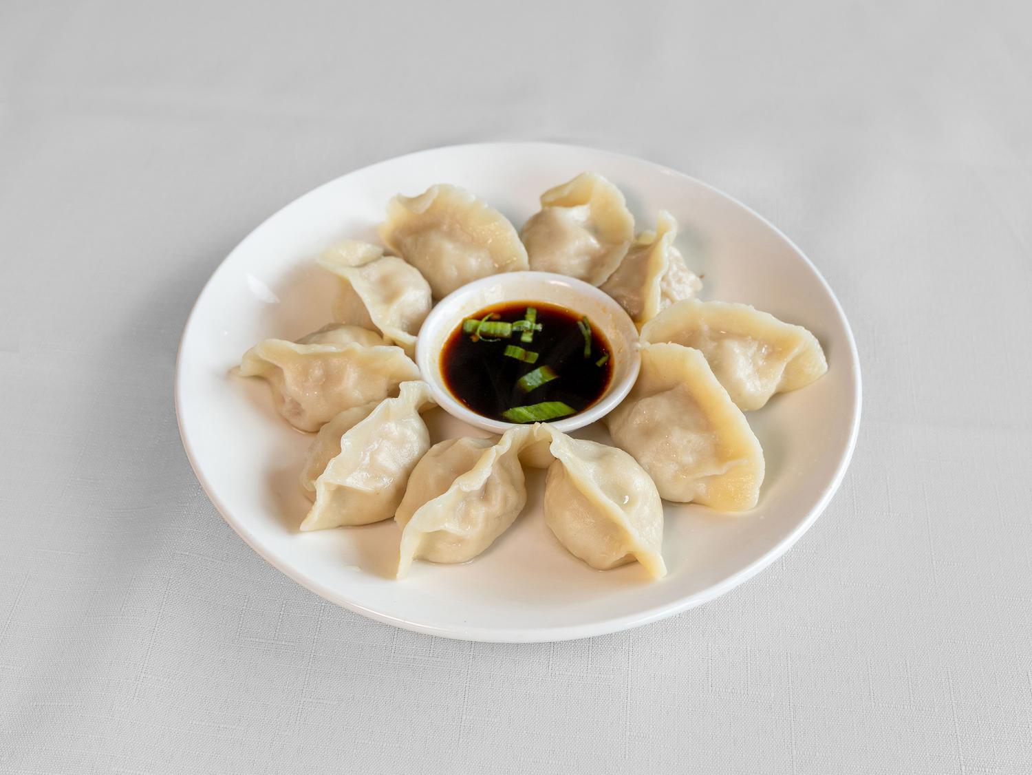 Steamed pork dumplings with soy dipping sauce on a white plate at Jia's House Restaurant, a Chinese Restaurant in Loma Linda