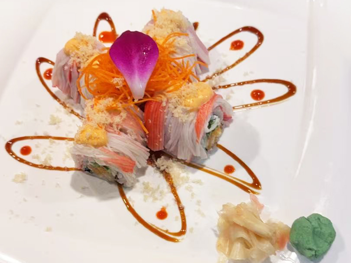 Japanese sushi roll topped with crab stick, shredded carrot, tempura bits, and garnished with orchid, served with pickled ginger and wasabi at Joe's Yummy Bowl，a Asian Restaurant in Flint