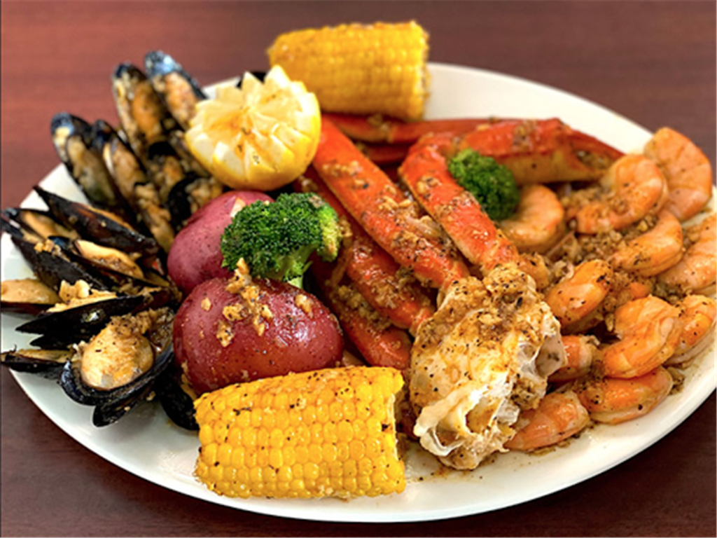 Seafood boil platter with crab legs, shrimp, mussels, corn, potato and broccoli