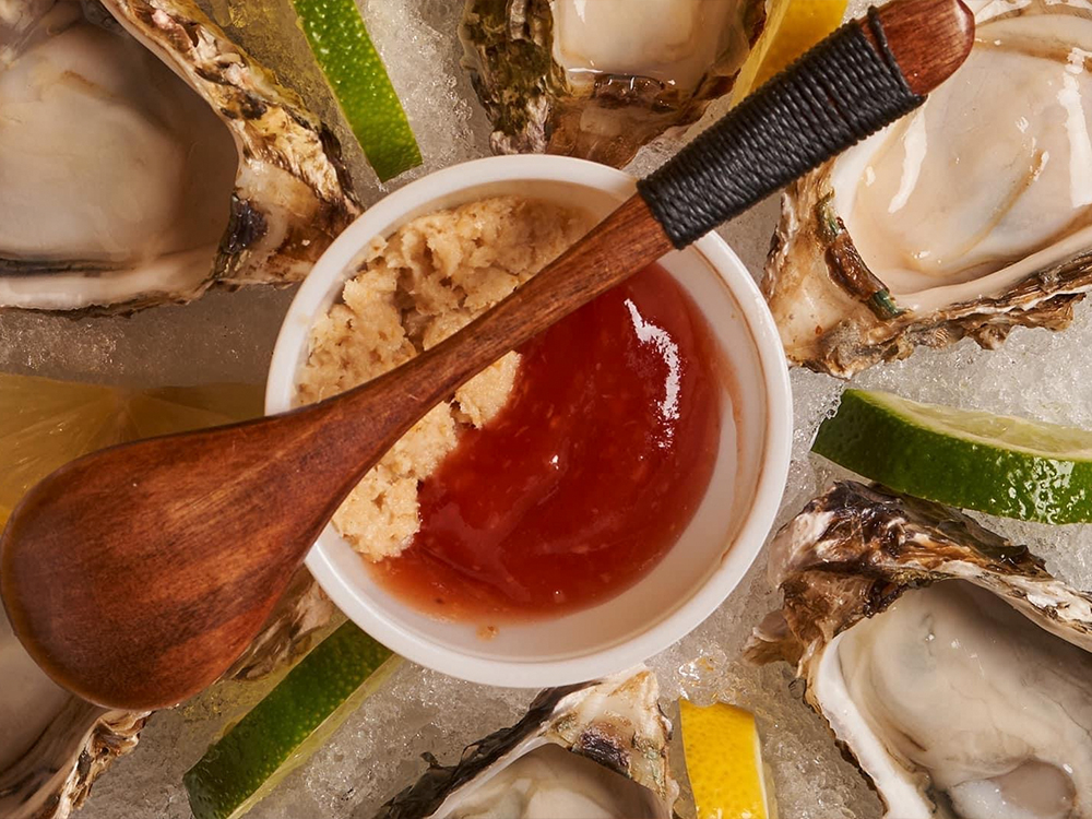 Fresh raw oysters on ice with cocktail sauce at The Juicy Seafood-Pearl, a Seafood in Pearl