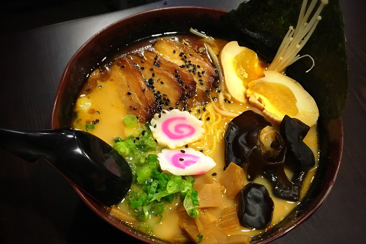 Ramen bowl with pork belly, soft-boiled eggs, mushrooms, narutomaki, and green onions